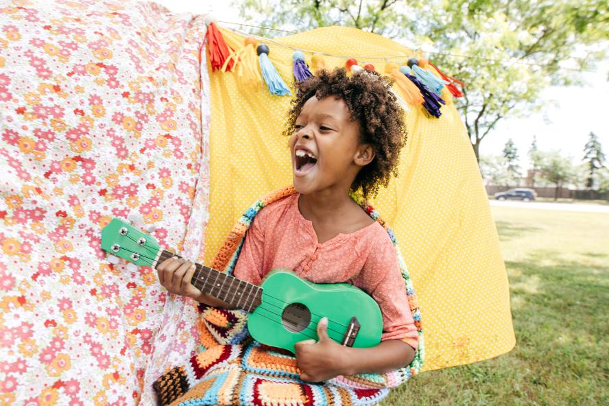 Child playing guitar outside